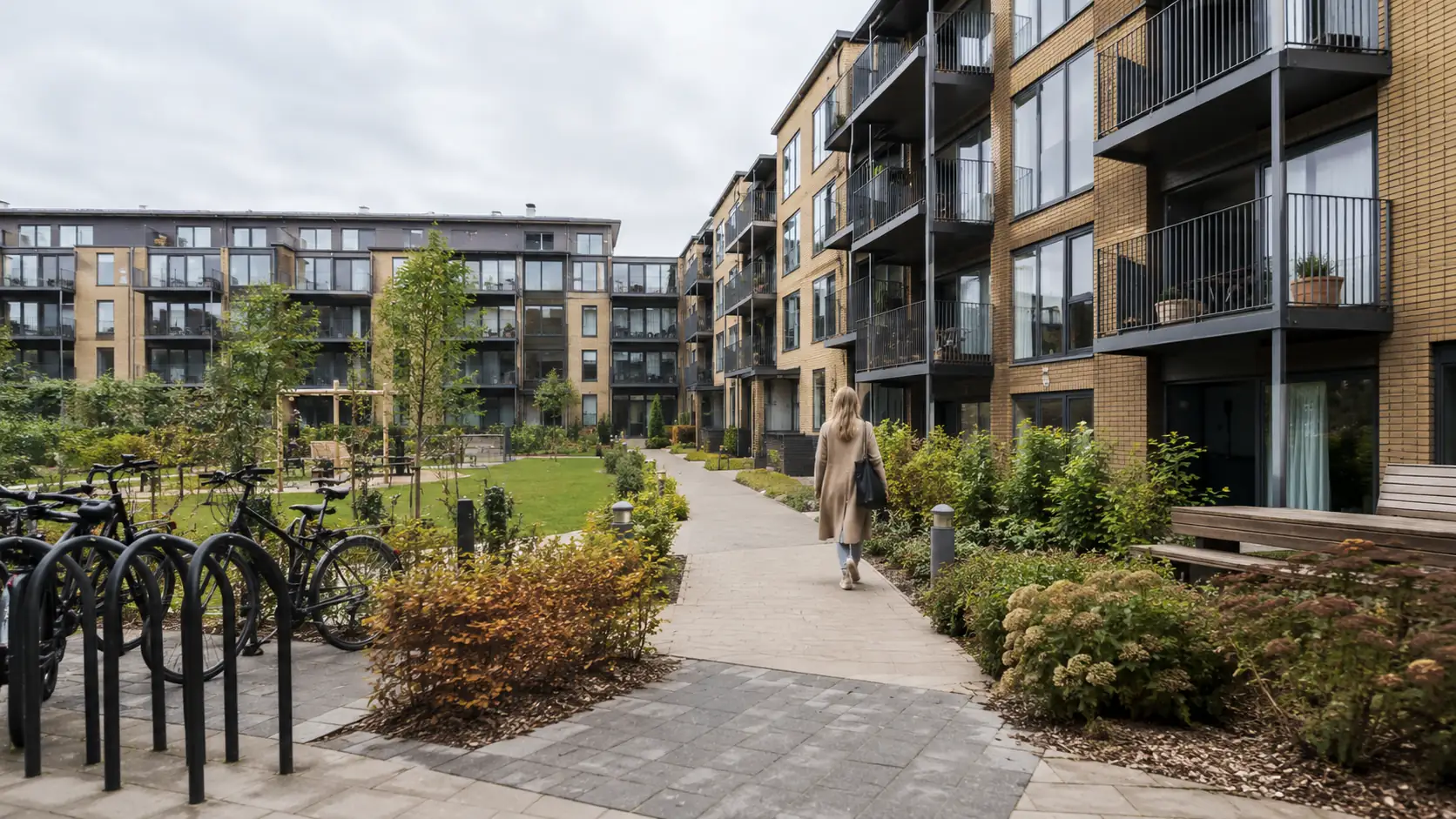 Apartment complex with green areas og there is a woman walking